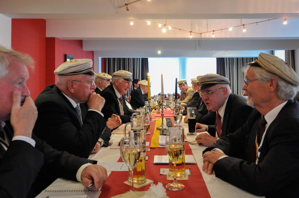 Mehrere Alte Herren sitzen an der Kneiptafel und unterhalten sich.
