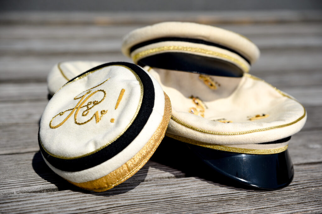 Mehrere Mützen und ein Tönnchen in den Farben Schwarz-Weiß-Gold.